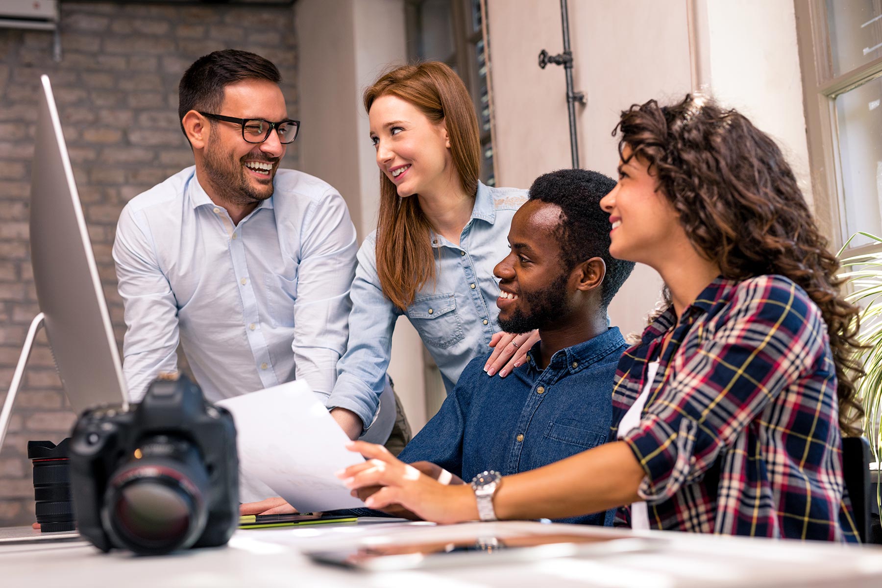 A group of students meeting and standing around a desktop computer