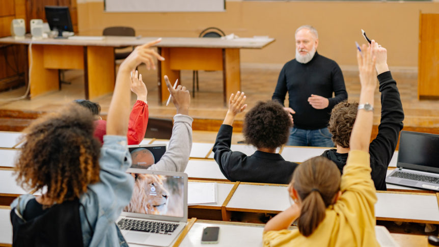 A professor observing his students raise their hands to interact.