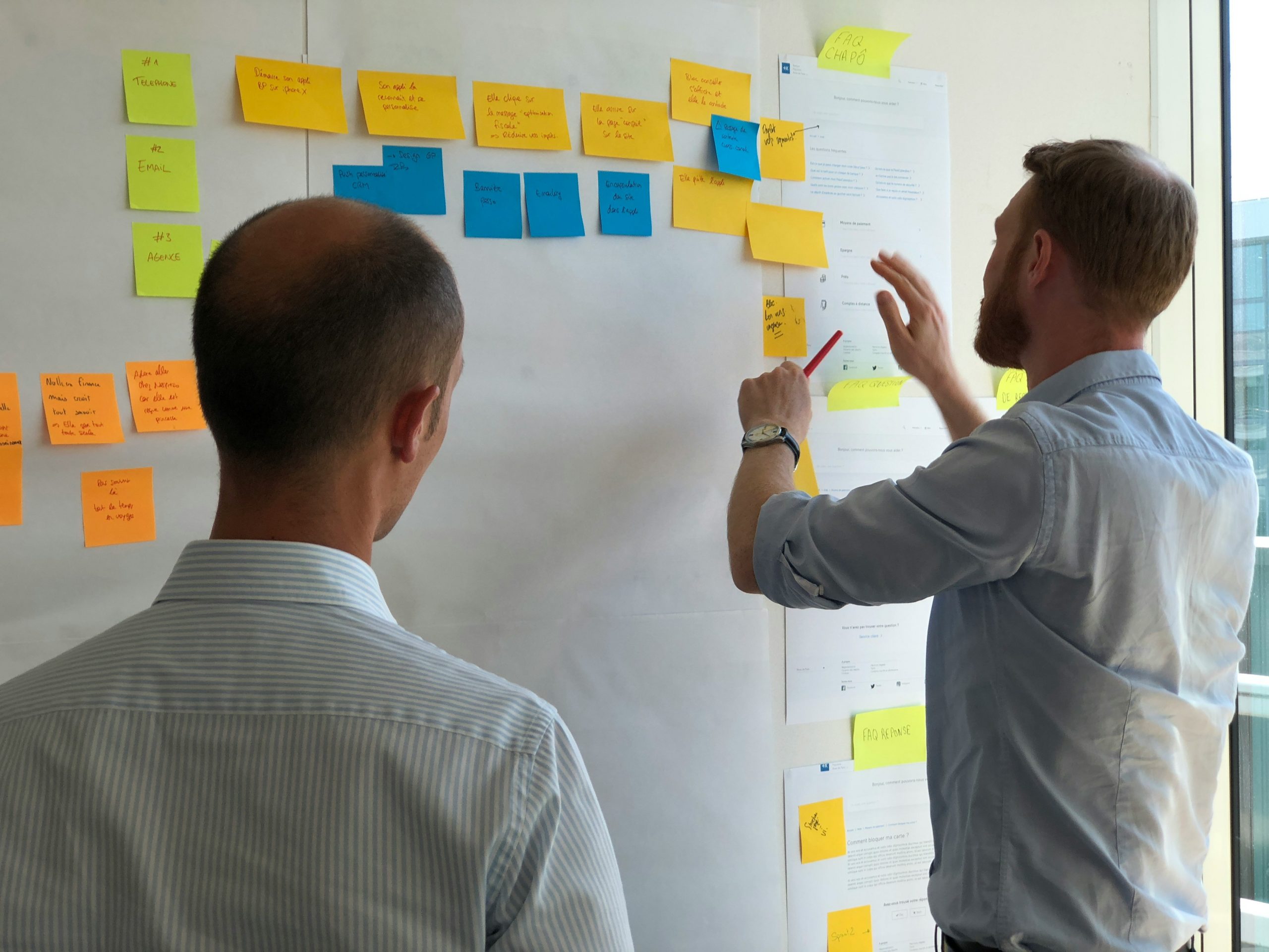 Two individuals planning with sticky notes on a whiteboard.